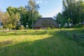 Old wooden shed with a high roof overgrown with moss. Standing in the depths of a rural courtyard with a wooden fence