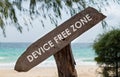 Old wooden sign with text device free zone on tropical beach