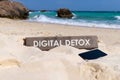 Old wooden sign with text digital detox on tropical beach