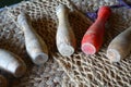 Old wooden skittles, played in medieval times, on a rough hessian backdrop. One of them is red Royalty Free Stock Photo