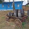 Old wooden small cart side by wooden house at a farm, on the dry grass Royalty Free Stock Photo