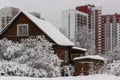 Old wooden house against the background of new tall city houses in winter Royalty Free Stock Photo