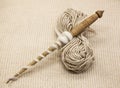 Old wooden spindle with a ball of wool thread for the manufacture of woolen threads on a tissue background Royalty Free Stock Photo