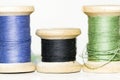 Old wooden spools of blue, green and black thread close up Royalty Free Stock Photo
