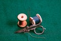 Old wooden spools with multicolored threads and scissors on green cloth. Retro still life. Close-up. Selective focus Royalty Free Stock Photo