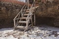 Old wooden staircase on the beach. Rustic ladder in stones on tropical beach. Ancient stairs on the rock.