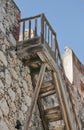 Old wooden stairs leading up to a rooftop of a historic building against a blue sky background. Weathered staircase and Royalty Free Stock Photo