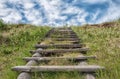 Old wooden stairway in green grass stretching into the sky Royalty Free Stock Photo