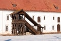 An old wooden stairways to the second floor outside. A stone white building with a red rusty roof. Sunny winter day Royalty Free Stock Photo