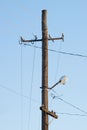 An old wooden street lamp against blue sky. Summer sunny day. Electric cable Royalty Free Stock Photo