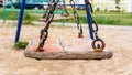 Old wooden swing on rusty metal chains in local playground Royalty Free Stock Photo