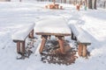 Old wooden table and bench covered with snow in the park Royalty Free Stock Photo