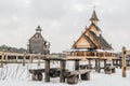 Old wooden table with benches in front of Ancient wooden Slavic church on a snowy landscape. Historical and Architectural Museum i