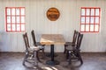 Old wooden table and chairs decorate in restaurant with red window on white wall in the background. Royalty Free Stock Photo