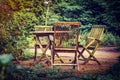 Old wooden table and chairs in the green garden of country house. Holidays in countryside in fresh air. Royalty Free Stock Photo