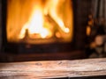 Old wooden table and fireplace with warm fire on the background Royalty Free Stock Photo