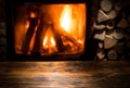 Old wooden table and fireplace with warm fire at the background Royalty Free Stock Photo