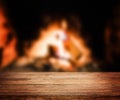 Old wooden table and fireplace with warm fire on the background. Royalty Free Stock Photo