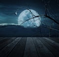 Old wooden table over bird, dead tree, moon and spooky cloudy sk Royalty Free Stock Photo