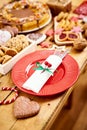 Wooden table with a red plate with knife and fork and various decorations