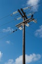 Old wooden three-phase electric utility pole with blue sky in background Royalty Free Stock Photo