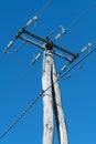 Old wooden three-phase electric utility pole with clear blue sky in background Royalty Free Stock Photo