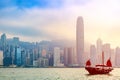 Old wooden tourist junk ferry boat in Victoria Harbor against famous Hong Kong island view with skyscrapers during sunrise Royalty Free Stock Photo