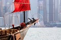 Old wooden tourist junk ferry boat in Victoria Harbor and famous Hong Kong island view with observation wheel Royalty Free Stock Photo