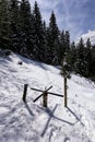 Old wooden turnstile in the snowy hillside by the forest