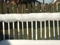 Old wooden village fence covered with snow. Snowy winter in the Royalty Free Stock Photo