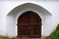 Old wooden vintage door with iron forged gate valve in a white wall Royalty Free Stock Photo