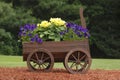Garden decoration of wooden wagon with purple and yellow flowers Royalty Free Stock Photo
