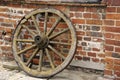 Old wooden wagon wheel in front of a brick wall. Royalty Free Stock Photo