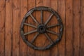 An old wooden wagon wheel hanging on a varnished wooden fence Royalty Free Stock Photo