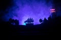 Old wooden warship sailing by night close to lighthouse or lighthouse and sailboat. Dark foggy background. Selective focus. Royalty Free Stock Photo