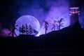 Old wooden warship sailing by night close to lighthouse or lighthouse and sailboat. Dark foggy background. Selective focus. Royalty Free Stock Photo