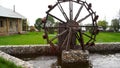 Old wooden water mill in country yard. Small wooden water mill spinning in a small pond, decoration in the garden Royalty Free Stock Photo