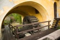 Old wooden watermill under yellow painted arches of ancient building Royalty Free Stock Photo