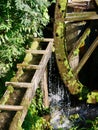 Old wooden waterwheel covered with moss. Flowing water to the mill. Royalty Free Stock Photo