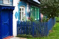 Old wooden and white brick house with green carved window frames, blue door and front garden fence Royalty Free Stock Photo