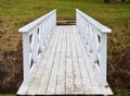 Old wooden white bridge on a grass background in autumn