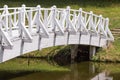 Old wooden white bridge over small pond or lake in city park. Concept of Asian garden design in summer time. Royalty Free Stock Photo