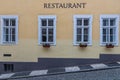 Old wooden white windows with flowers in old yellow building with Restaurant sign in Prague Royalty Free Stock Photo