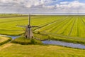 Old wooden windmill in green agricultural grassland