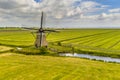 Old wooden windmill in green agricultural grassland