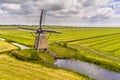 Old wooden windmill in green agricultural grassland