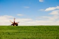 Old wooden windmill at horizon behind green field against blue sunny sky Royalty Free Stock Photo