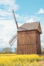 very old wooden windmill in rapseed field and sand road with clouds and blue sky in background Royalty Free Stock Photo