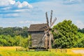 Old wooden windmill in a rural Central European setting, surrounded by greenery and clouds Weathered structure with multiple sails Royalty Free Stock Photo