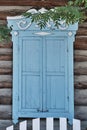 Old wooden window with closed worn blue shutters and carved architraves Royalty Free Stock Photo